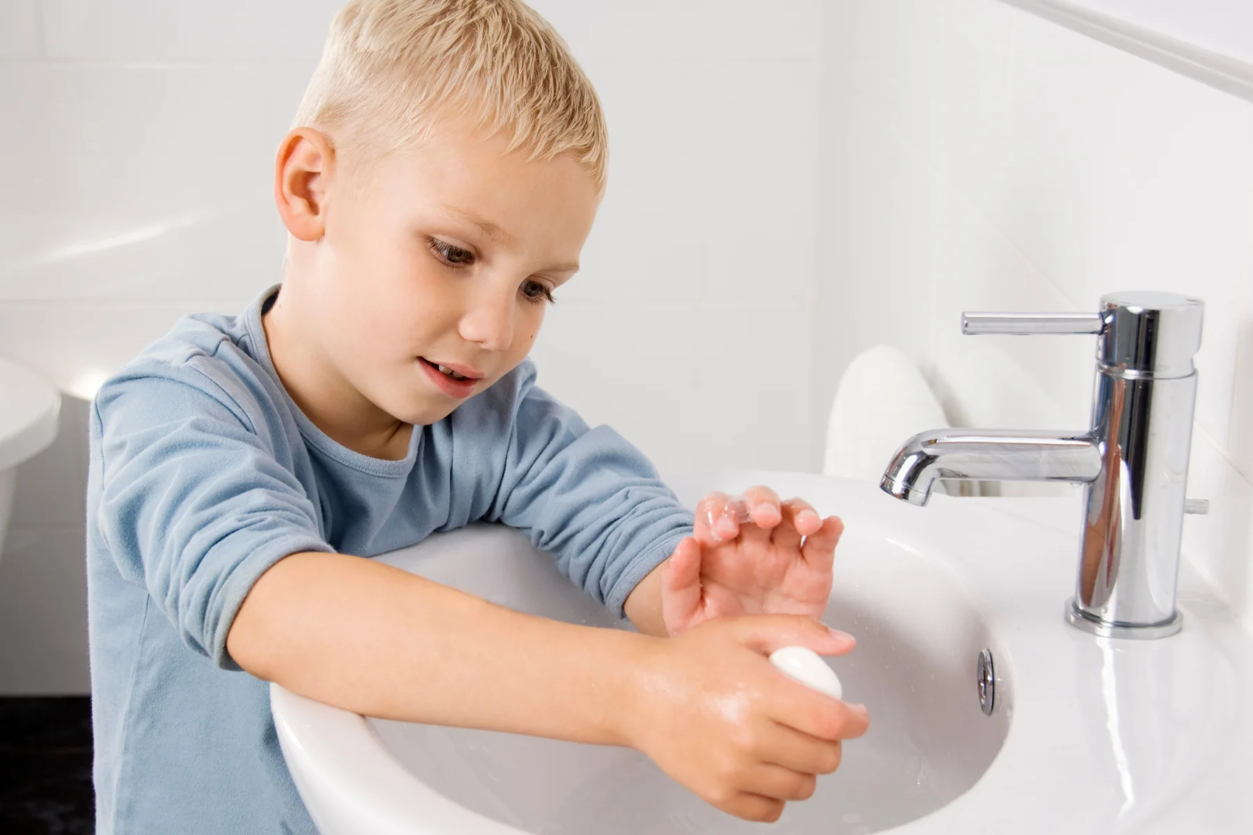 boy washing his hands at the sink with soap