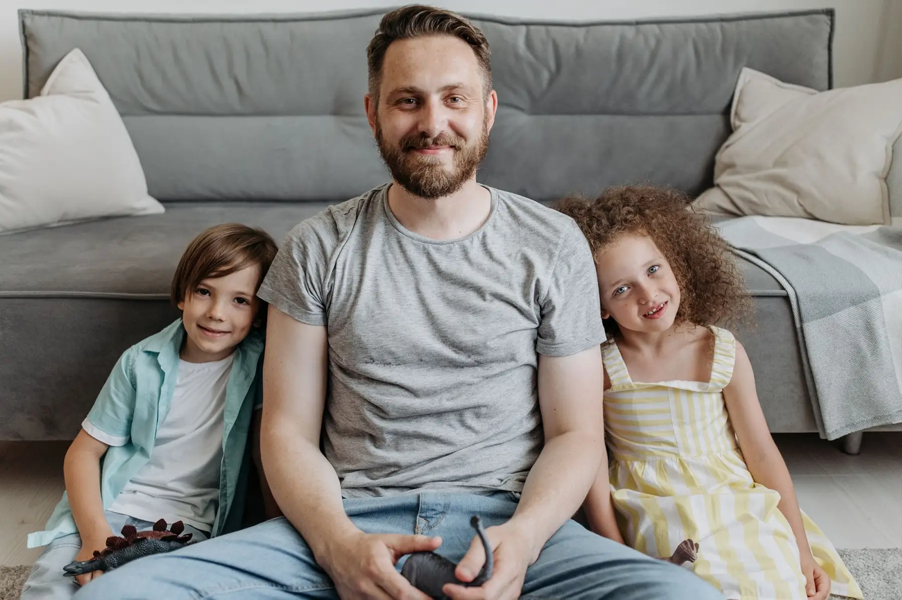 man on couch playing with his two children