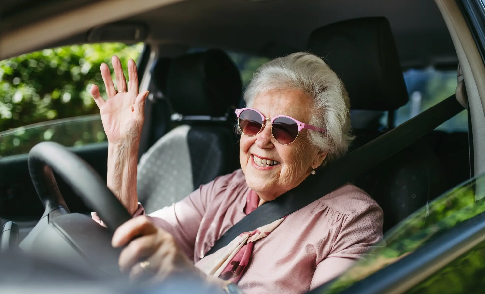 senior woman driving a car, waving