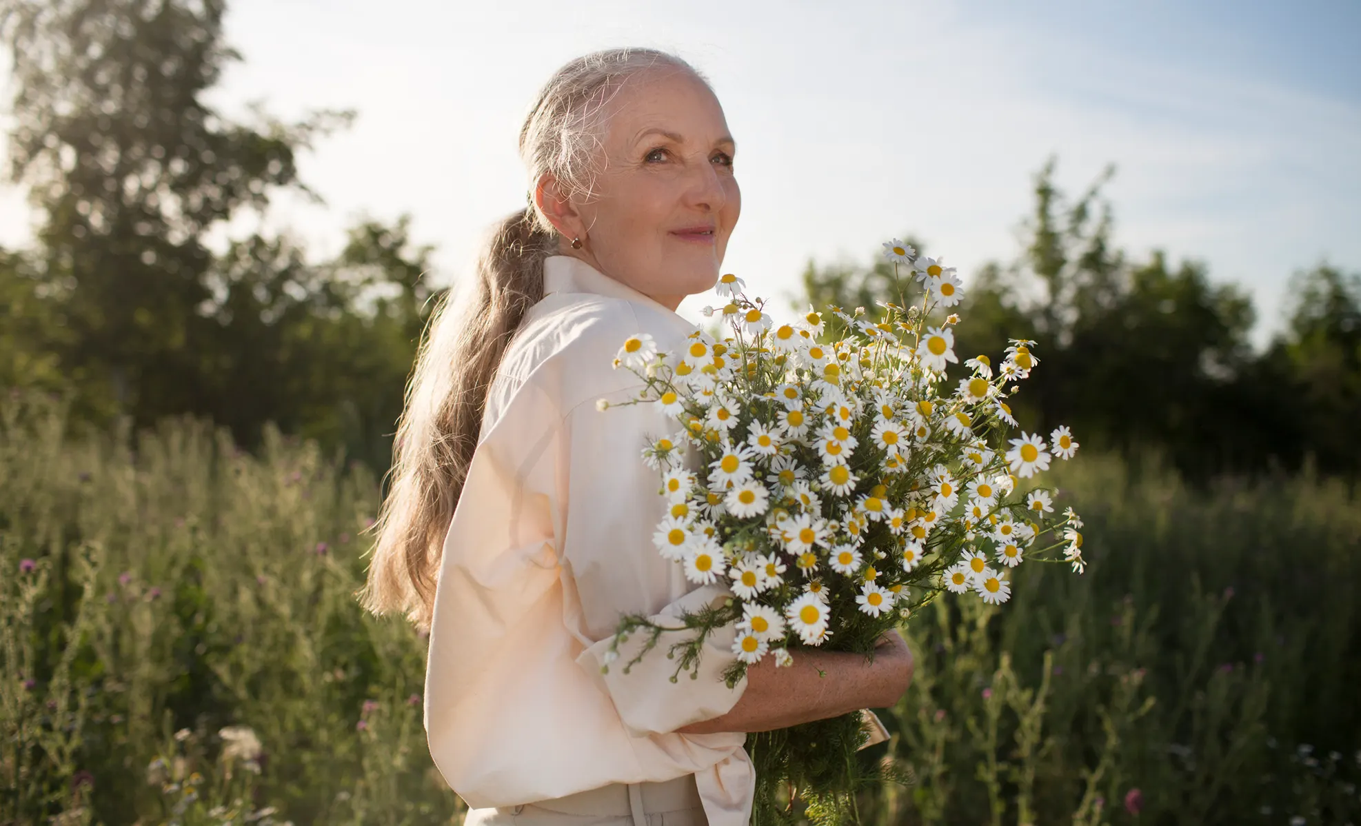 Older woman holding flowers outdoors