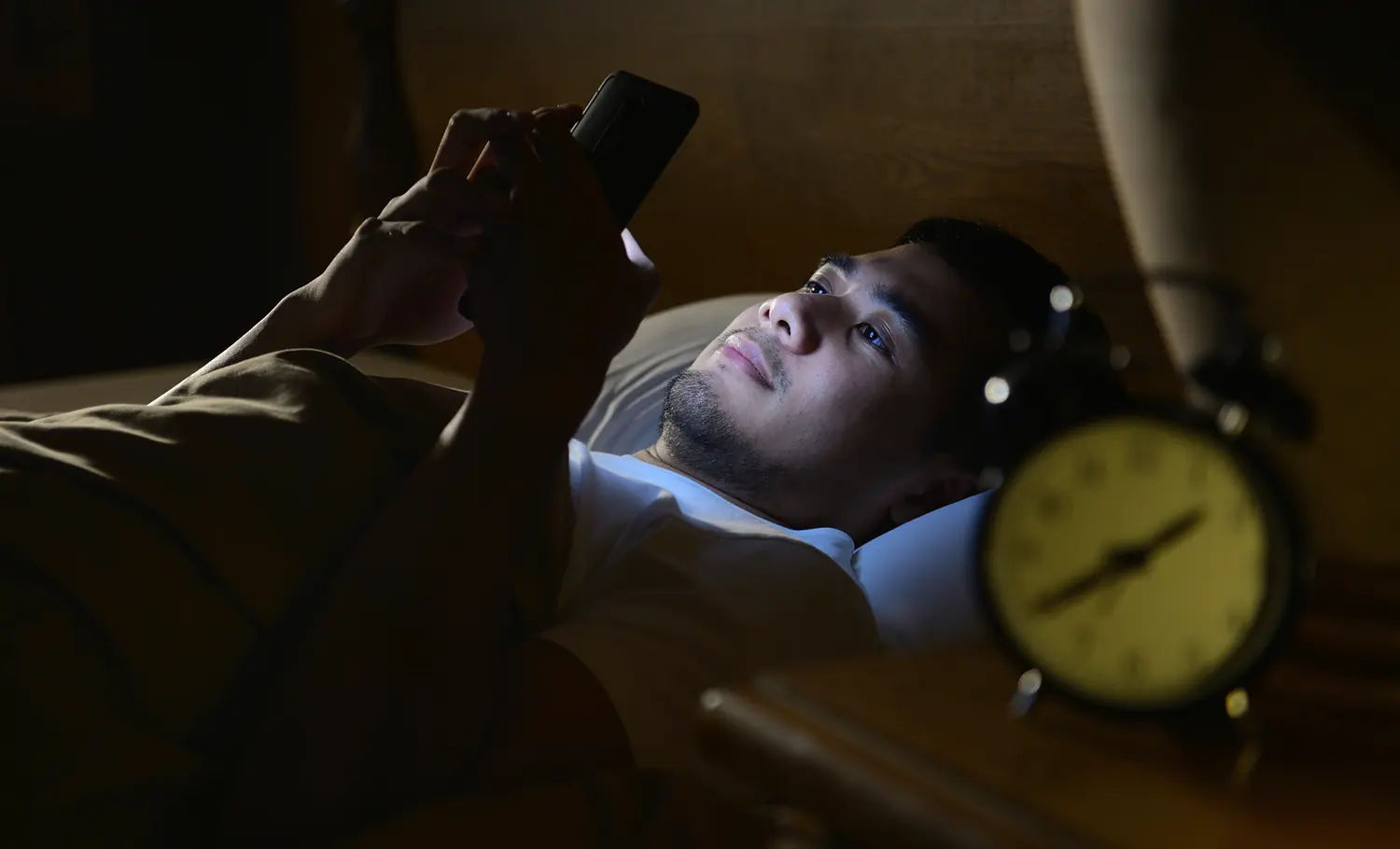 guy on cell phone in bed late at night