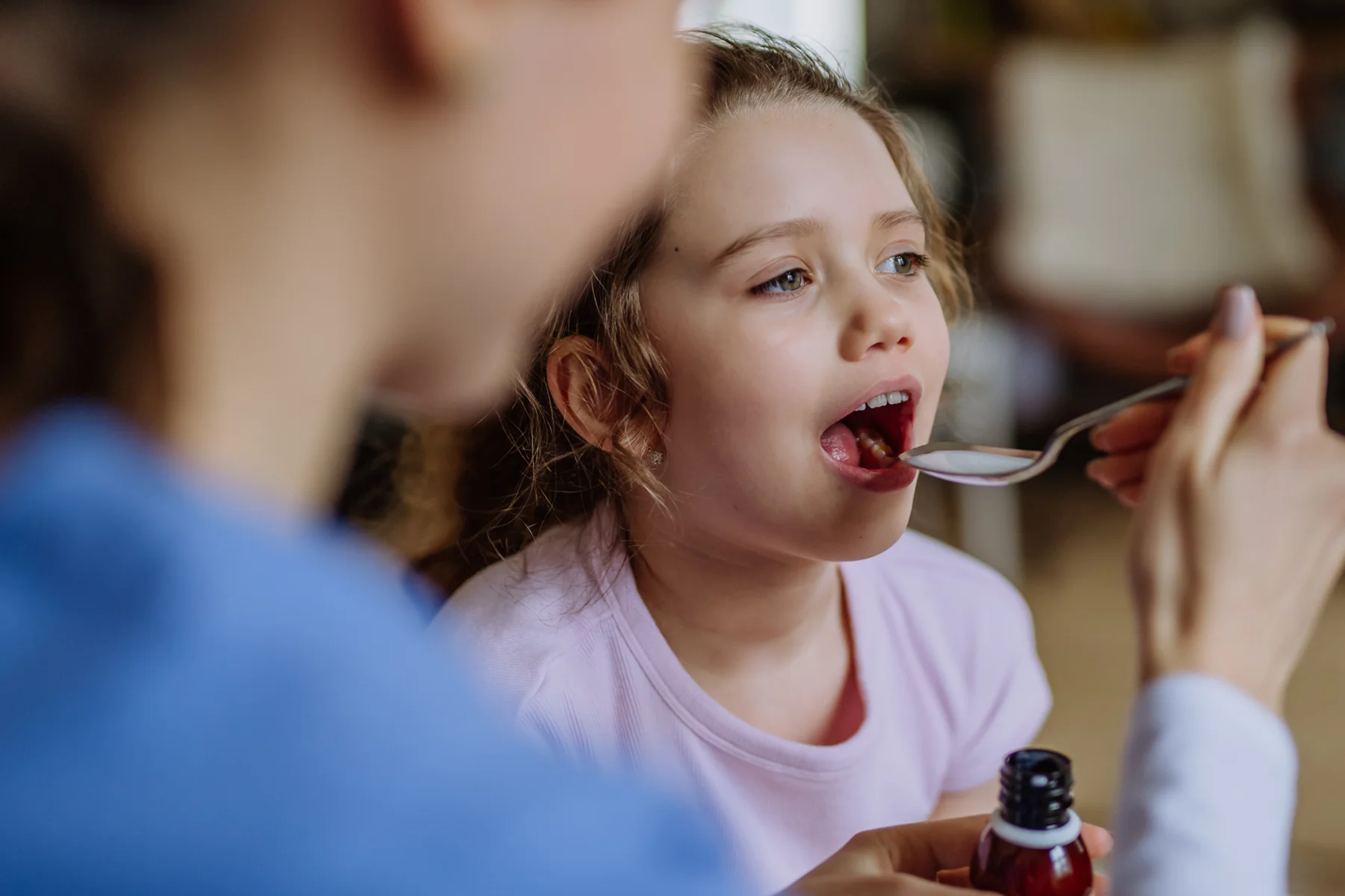 adult giving child liquid medicine