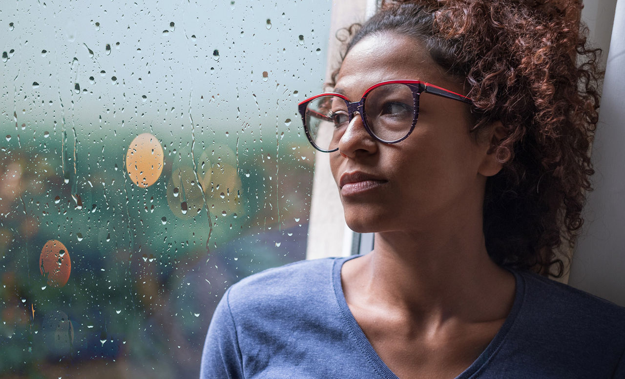 woman looking out a window while reflecting on her health