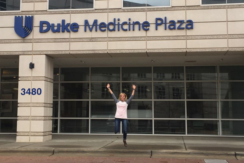 Carrie jumping in celebration outside of Duke Medicine after hearing she is cancer free