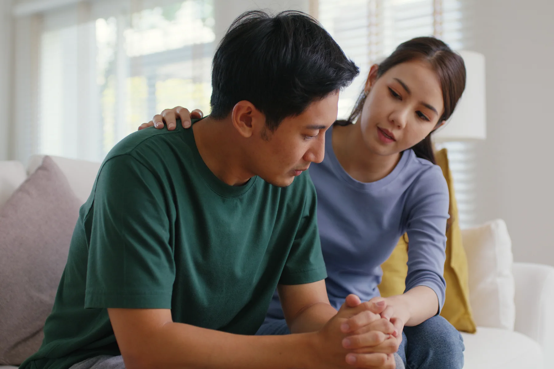 Couple sitting on the bed with the woman comforting the man
