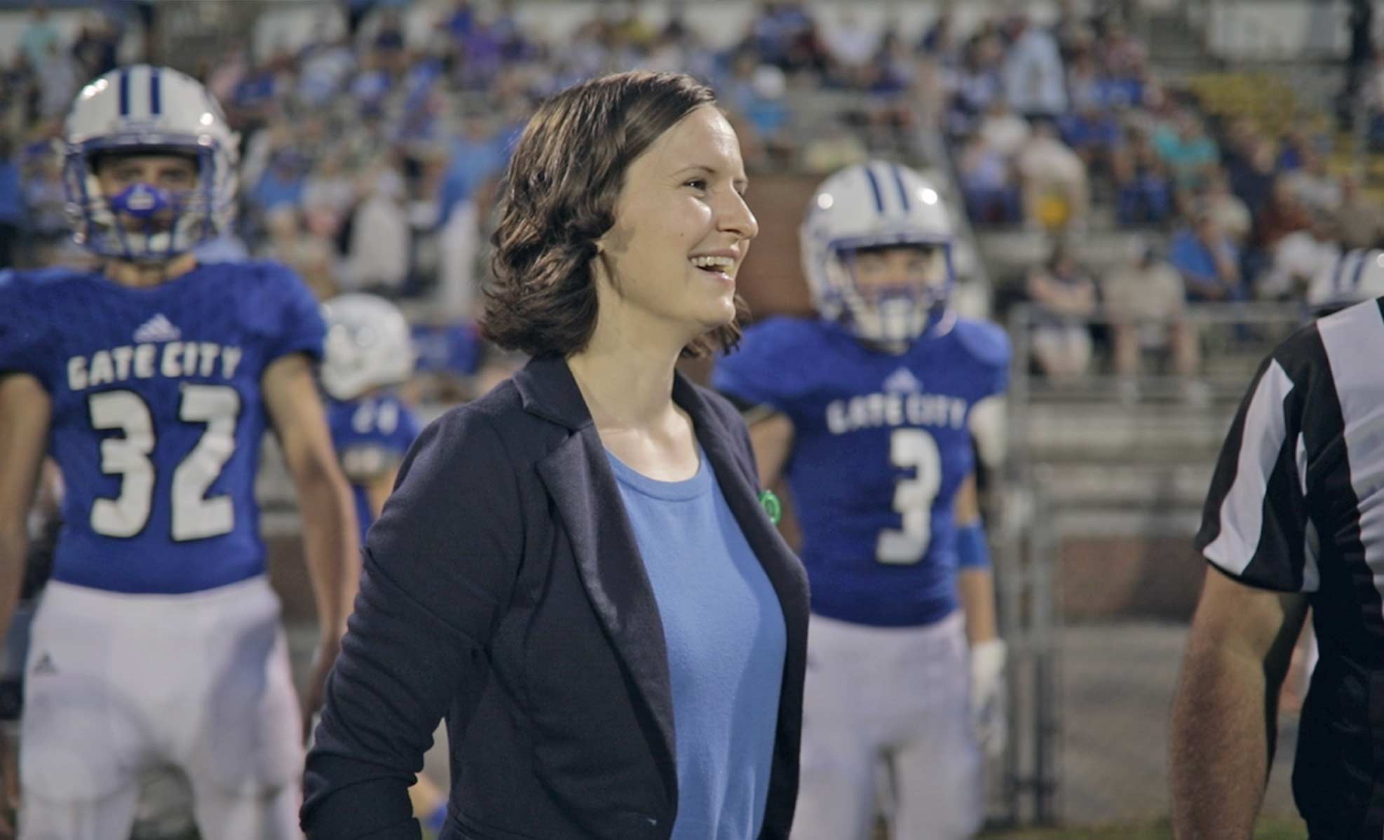 Dr. Remy with football players in the background during a game