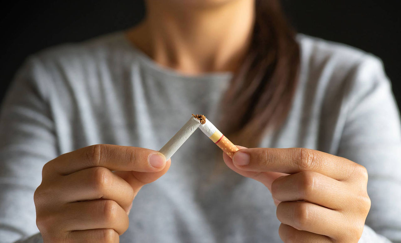 person tearing a cigarette in half