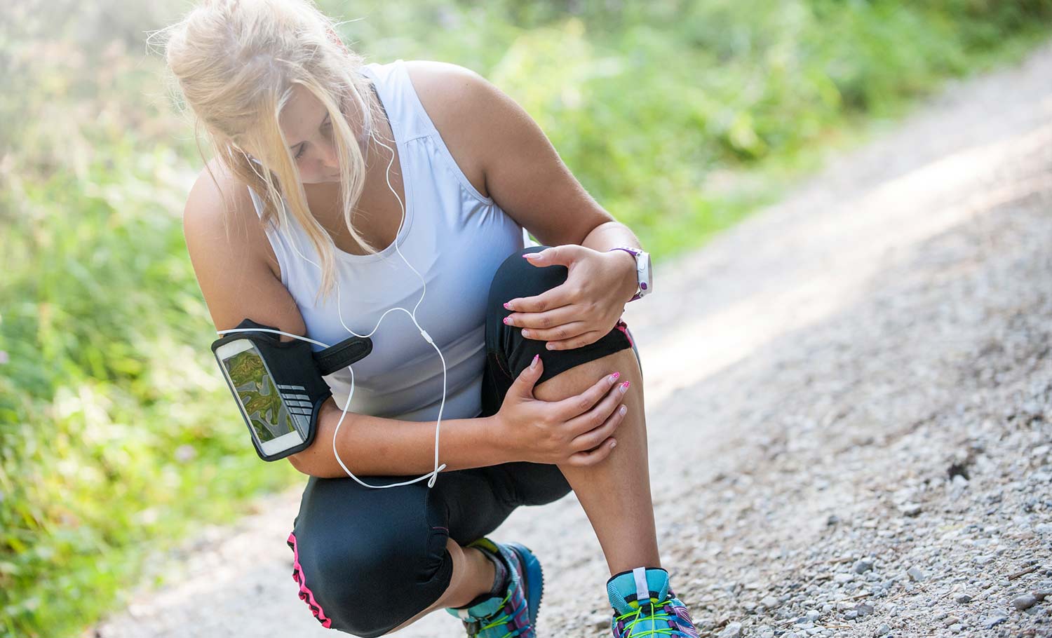 Young adult female athlete holding her leg from cramps while running