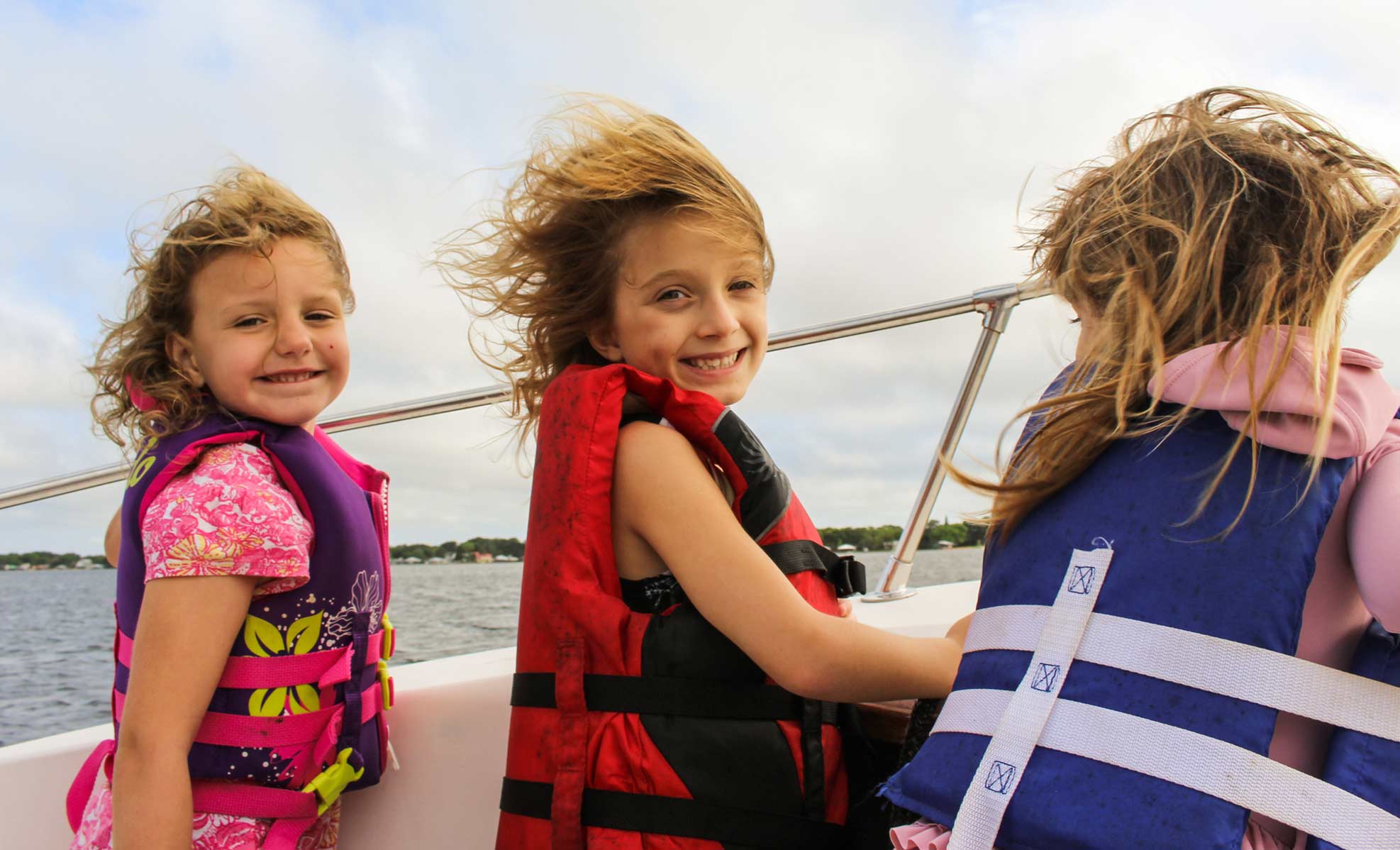 kids with life jackets on while on a boat
