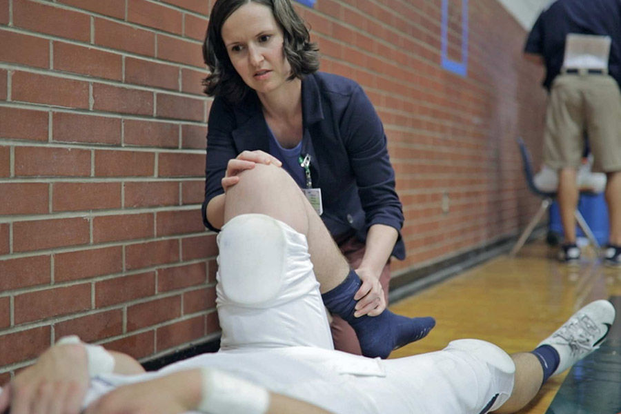 Sports medicine physician examining the knee of a football player