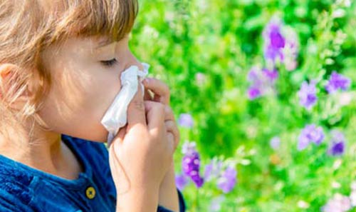 girl suffering from allergies, blowing her nose