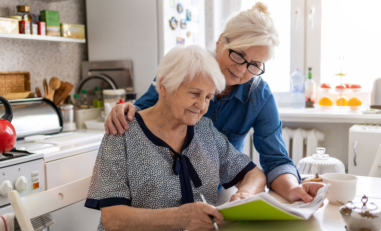 senior and daughter at kitchen table working on a plan